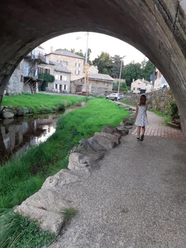 a girl walking under a bridge over a river at Appartement rez de chaussée avec terrasse et jardin à Tence in Tence