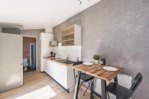 a small kitchen with a wooden table and a sink at Le Patio Champenois in Reims