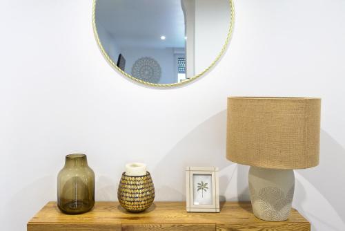 a table with vases and a lamp and a mirror at Hôtel Lodge In Paris 13 in Paris