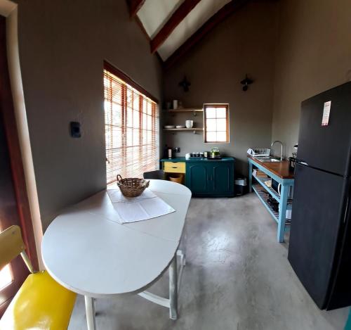 a kitchen with a white table and a refrigerator at A cozy, artistic suburban-stay at Alice in Africa in Rooihuiskraal