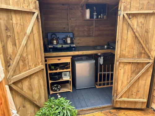 a kitchen with a refrigerator and a sink in a barn at Bracken Barns Glamping & Massage in Minishant