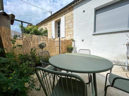 a green table and chairs on a patio at Charmante maison proche Bordeaux in Lormont