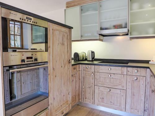 a large kitchen with wooden cabinets and appliances at Apartment Chalet Smaragd-3 by Interhome in Grindelwald