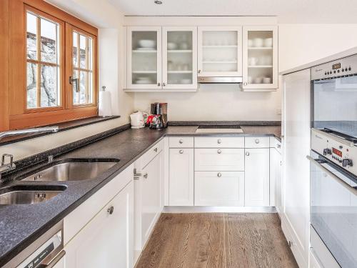 a kitchen with white cabinets and a wooden floor at Apartment Chalet Smaragd-1 by Interhome in Grindelwald