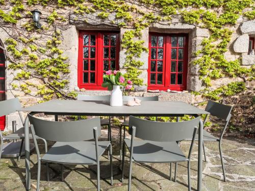 ein Tisch und Stühle vor einem Gebäude mit roten Fenstern in der Unterkunft Holiday Home Dolce Vita by Interhome in Plouha