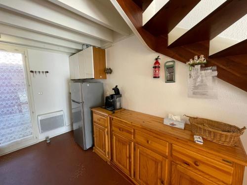 une cuisine avec des armoires en bois et un réfrigérateur dans l'établissement Villa patio proche du port, à Capbreton