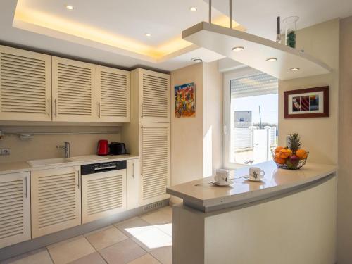 une cuisine avec des armoires blanches, un évier et une fenêtre dans l'établissement Holiday Home Ty Pors Ar Pagn by Interhome, à Penmarcʼh