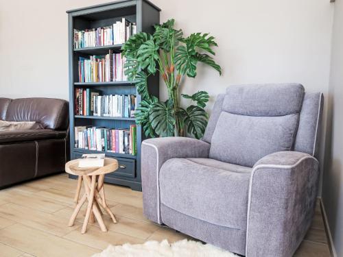 a living room with a chair and a book shelf with books at Holiday Home Orphée by Interhome in Telgruc-sur-Mer