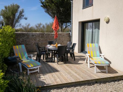 a wooden deck with chairs and a table with an umbrella at Holiday Home Tal ar Mor by Interhome in Plouescat