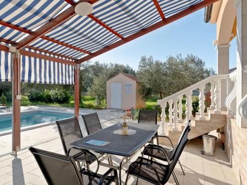 Un patio con mesa y sillas y una piscina. en Holiday Home Danijel by Interhome, en Sukošan