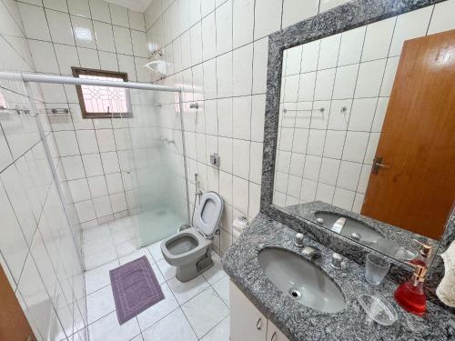 a bathroom with a sink and a toilet and a mirror at Casa p/ 11 hóspedes - 900m do Parque de Exposições in Patos de Minas