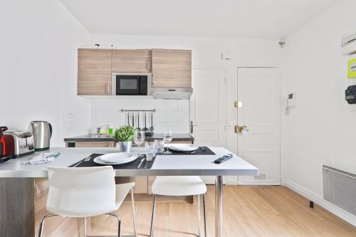 une cuisine blanche avec une table et des chaises blanches dans l'établissement Studio Appartement Quartier Tour Eiffel 10 Free Netflix, à Paris