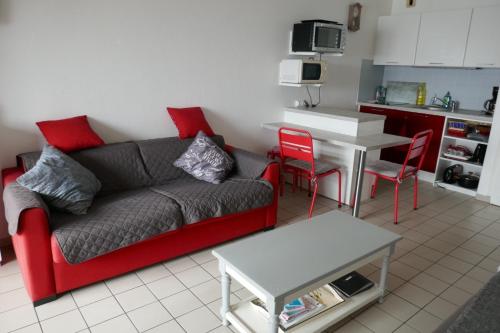 un salon avec un canapé rouge et une table dans l'établissement Studio à saint gilles croix de vie 4 personnes, à Saint-Gilles-Croix-de-Vie