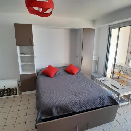 une chambre avec un lit avec deux oreillers rouges dans l'établissement Studio à saint gilles croix de vie 4 personnes, à Saint-Gilles-Croix-de-Vie