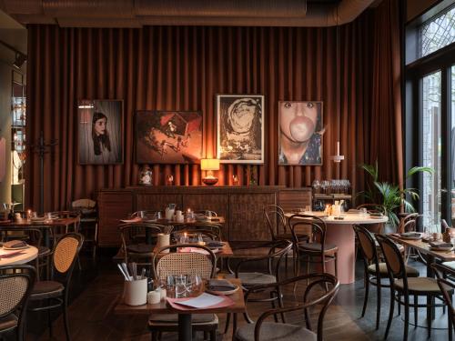 a restaurant with tables and chairs and paintings on the wall at lyf East Frankfurt in Frankfurt