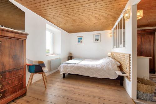 Maison pour 6 avec jardin, terrasse et jeux في Saint-Frégant: غرفة نوم بها سرير وسقف خشبي