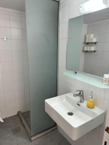 a white bathroom with a sink and a mirror at Elio A 1BDR Apt with Garden 1 min from the beach by Hospi in Heraklio Town
