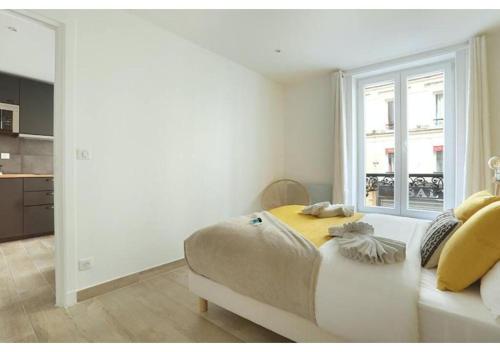 une chambre blanche avec un grand lit avec une fenêtre dans l'établissement Apartment Center of Paris by Studio prestige, à Paris