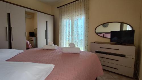 a bedroom with a pink bed with a mirror and a tv at Anatoli Kavala in Kavála