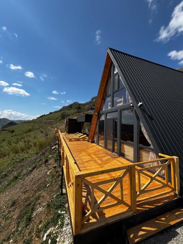 a wooden house with a black roof on a hill at Dream view of Apuseni in Rîmeţi