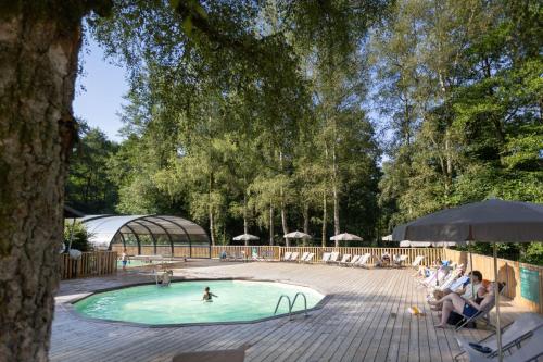 a swimming pool with people sitting in chairs around it at Huttopia Caminos de Galicia in Prado