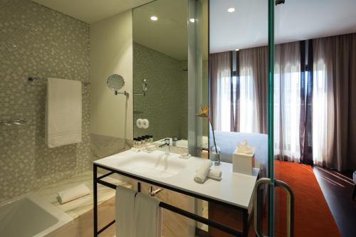 a bathroom with a sink and a shower and a tub at Pestana Porto - A Brasileira, City Center & Heritage Building in Porto