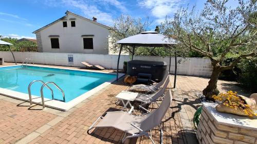 a swimming pool with two chairs and an umbrella at Apartments Kimm's Hideaway in Poreč
