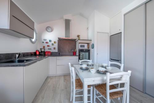 a kitchen with white cabinets and a table and chairs at Appart dans bourg a 230m de la plage - 4 pers in La Bernerie-en-Retz