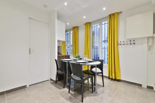 une salle à manger avec une table et des rideaux jaunes dans l'établissement Heart of Paris - 2BR - 6P - Le Marais 8 Free Netflix, à Paris