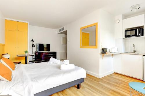 Cet appartement comprend une chambre avec un lit blanc et une cuisine. dans l'établissement Eiffel residence Joséphine, à Paris