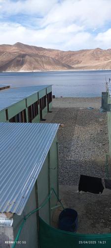 a building with a blue roof next to a body of water at Pangong Destination in Spangmik
