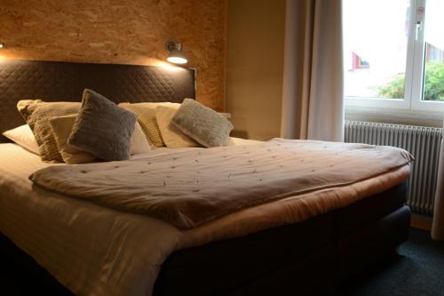 a large bed in a bedroom with a large window at Hotel SPA Au Cheval Blanc in Ribeauvillé