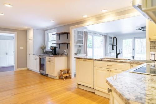 a large kitchen with white cabinets and wooden floors at Private and Peaceful 4BD Home in Wayland