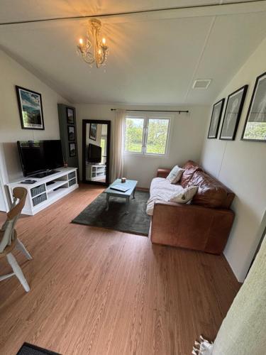 a living room with a couch and a tv at The Lodge, dog friendly rural retreat in Llandeilo
