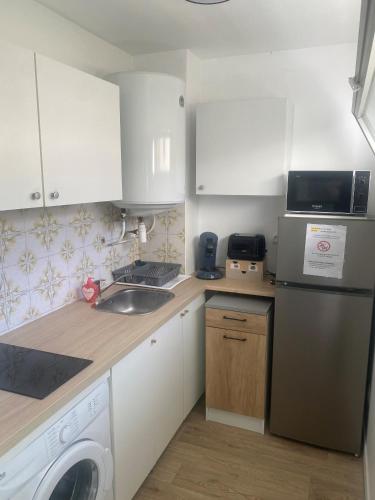 une cuisine avec des armoires blanches et une laveuse et une sécheuse dans l'établissement Studio 29 Nice Magnan, à Nice