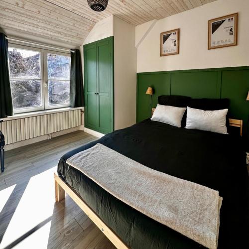 une chambre avec un grand lit aux murs verts dans l'établissement Havre de paix 1h30 de Paris, à Champigny-sur-Yonne