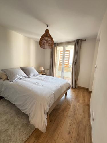 une chambre avec un grand lit et une grande fenêtre dans l'établissement Charmant appartement cosy proche des plages, à Fréjus