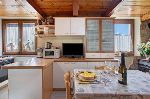 a kitchen with a table with a bottle of wine at Eun Tchì Vo - Gignod in Gignod