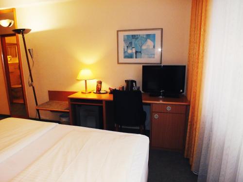 a hotel room with a bed and a desk with a television at Werrapark Resort Hotel Frankenblick in Masserberg