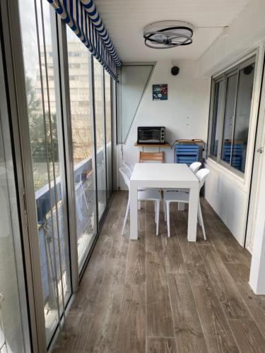 une salle à manger avec une table blanche sur un balcon dans l'établissement Bleu Soleil, à La Grande Motte