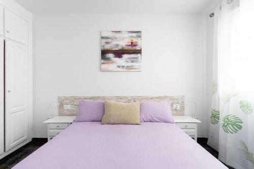 a bedroom with a white bed with purple pillows at Ático San Juan Teide View in Playa de San Juan