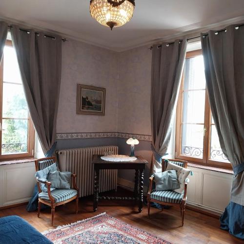 a room with two chairs and a table and windows at Le coq en pâte in Bussang