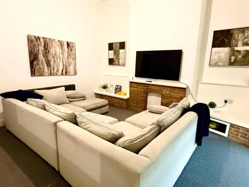 a living room with a large couch and a fireplace at Brand New Lovely Flats by the Forest Tram Stop in Nottingham in Nottingham