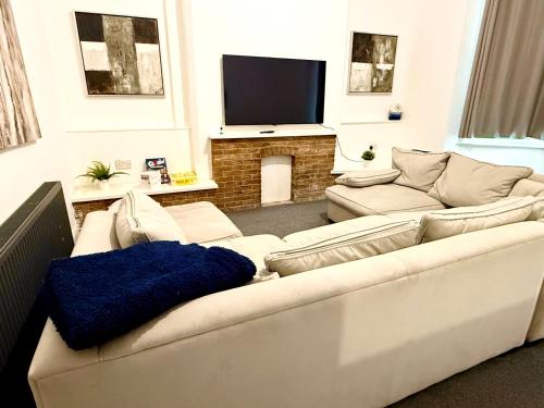 a living room with a white couch and a fireplace at Brand New Lovely Flats by the Forest Tram Stop in Nottingham in Nottingham