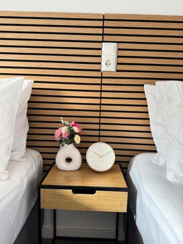 a nightstand between two beds with a clock and flowers at Mahesars Home in Gevelsberg