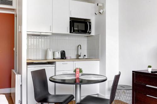 une petite cuisine avec une table et des chaises dans l'établissement Eiffel résidence Simone, à Paris