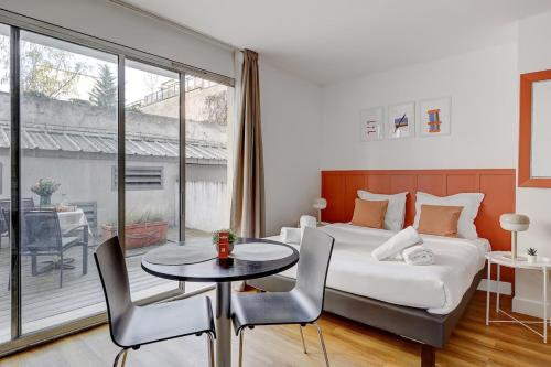 une chambre avec un lit, une table et des chaises dans l'établissement Eiffel résidence Simone, à Paris