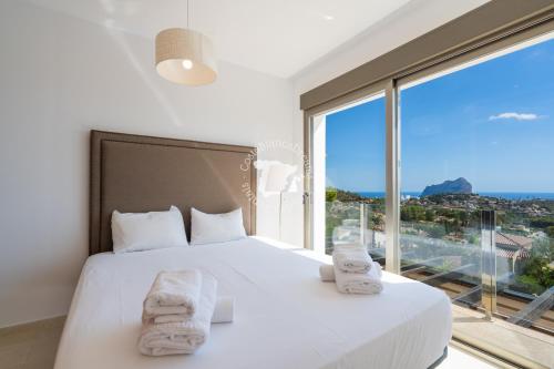 a bedroom with a white bed and a large window at CostaBlancaDreams Casa con Vista in Calpe in Empedrola