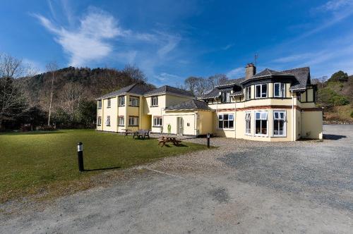a large house with a grass yard in front of it at Glendalough International Youth Hostel in Laragh