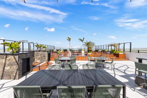 a patio with tables and chairs on a roof at Alta Garden Housi João Pessoa by Carpediem in João Pessoa